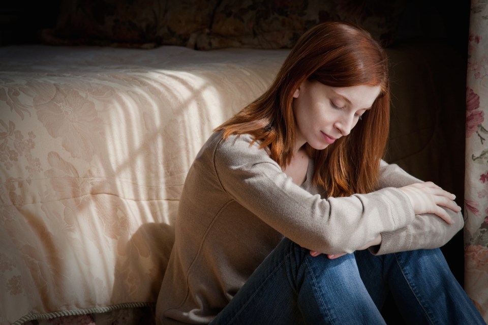 a woman sits on the floor in front of a bed