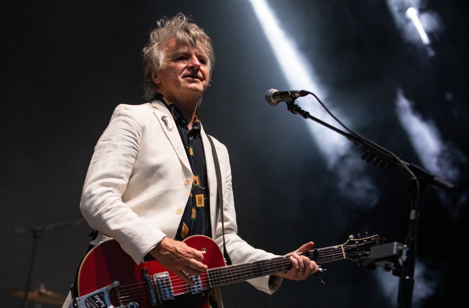 a man in a white jacket playing a red guitar