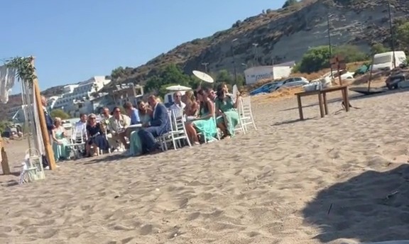 a group of people sit at tables on a sandy beach