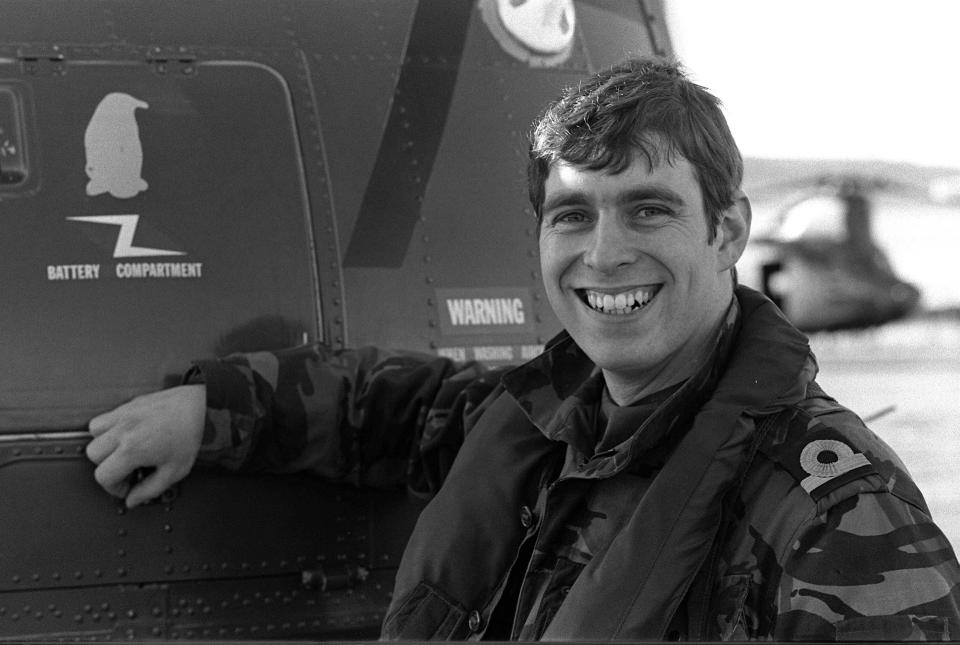 a man in a military uniform is smiling in front of a warning sign