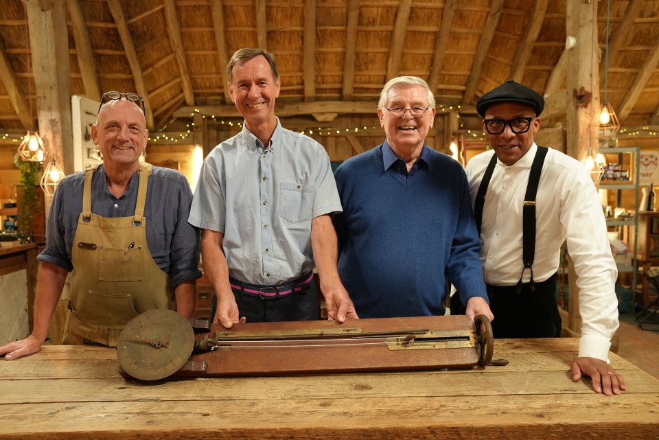 four men standing around a wooden table with a clock on it