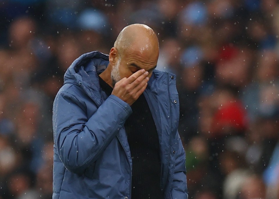 a man in a blue jacket wipes his face with his hand