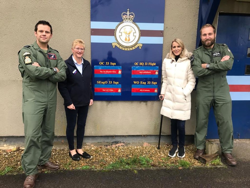 four people stand in front of a sign that says oc 33 sqn