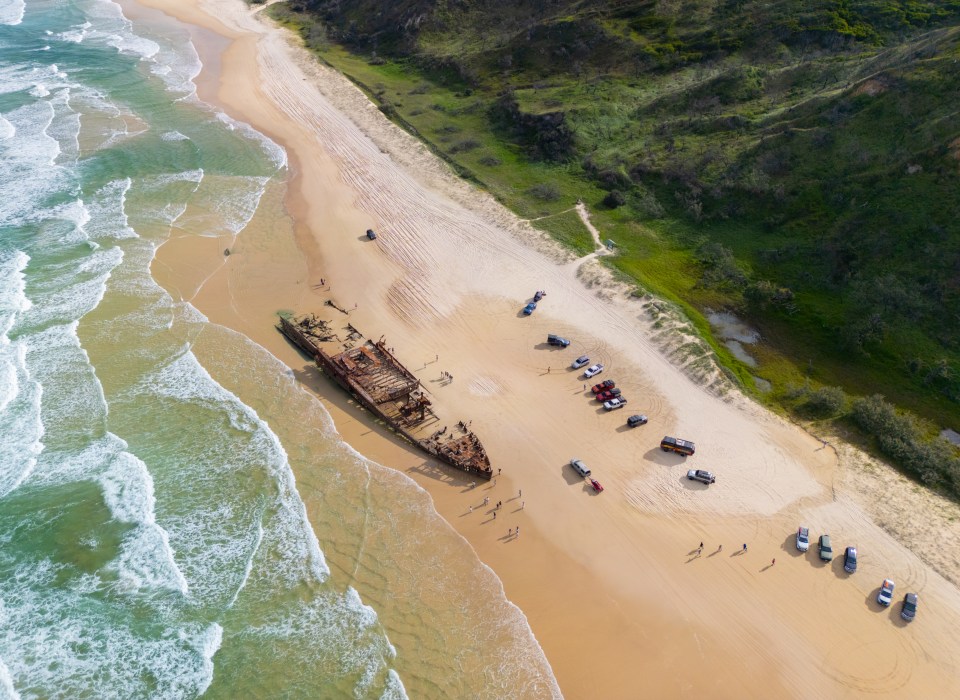 an aerial view of a beach with boats on the sand