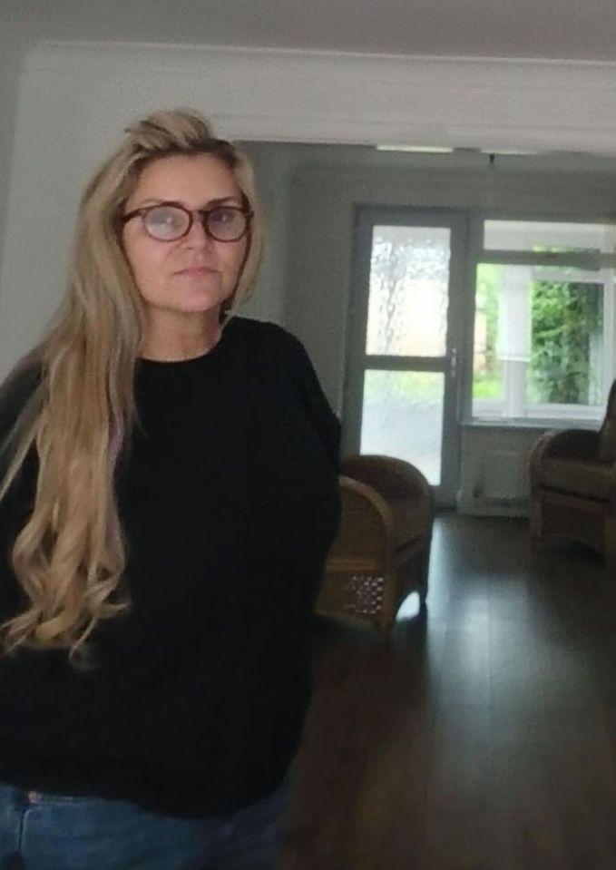 a woman wearing glasses and a black sweater stands in a living room