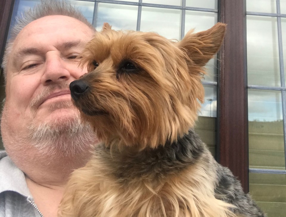 a man holds a small dog in front of a window