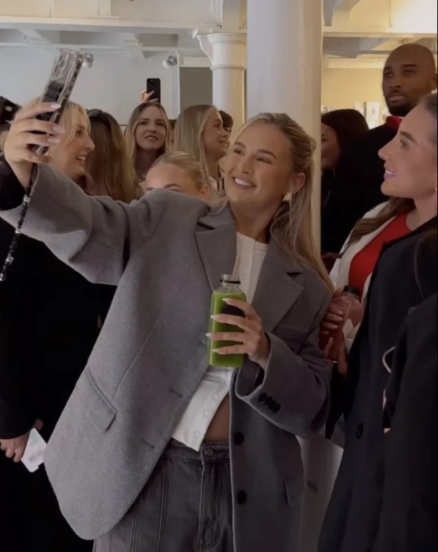 a woman taking a selfie with a green bottle in her hand