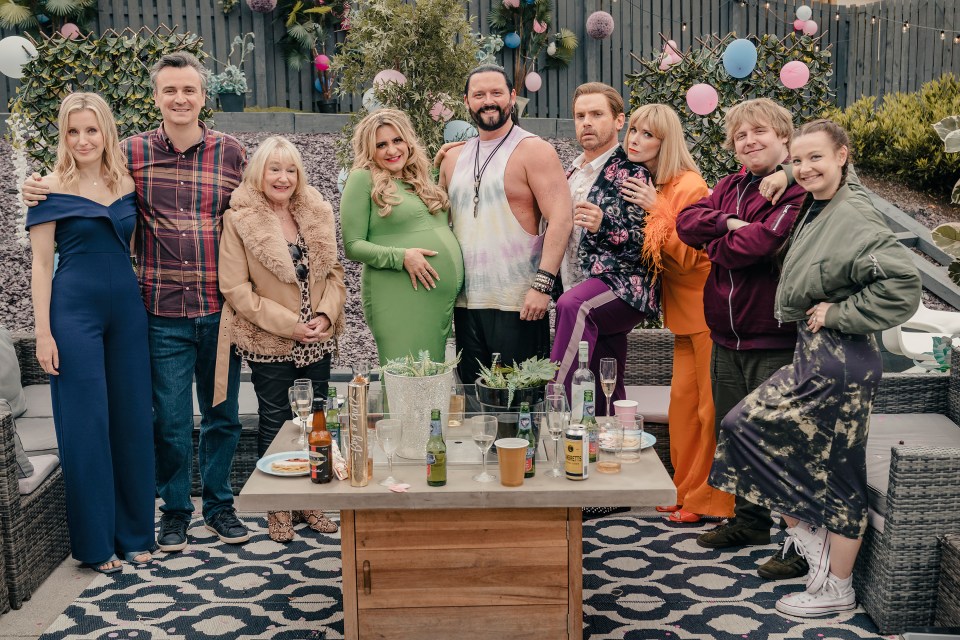 a group of people standing around a table with bottles of alcohol on it