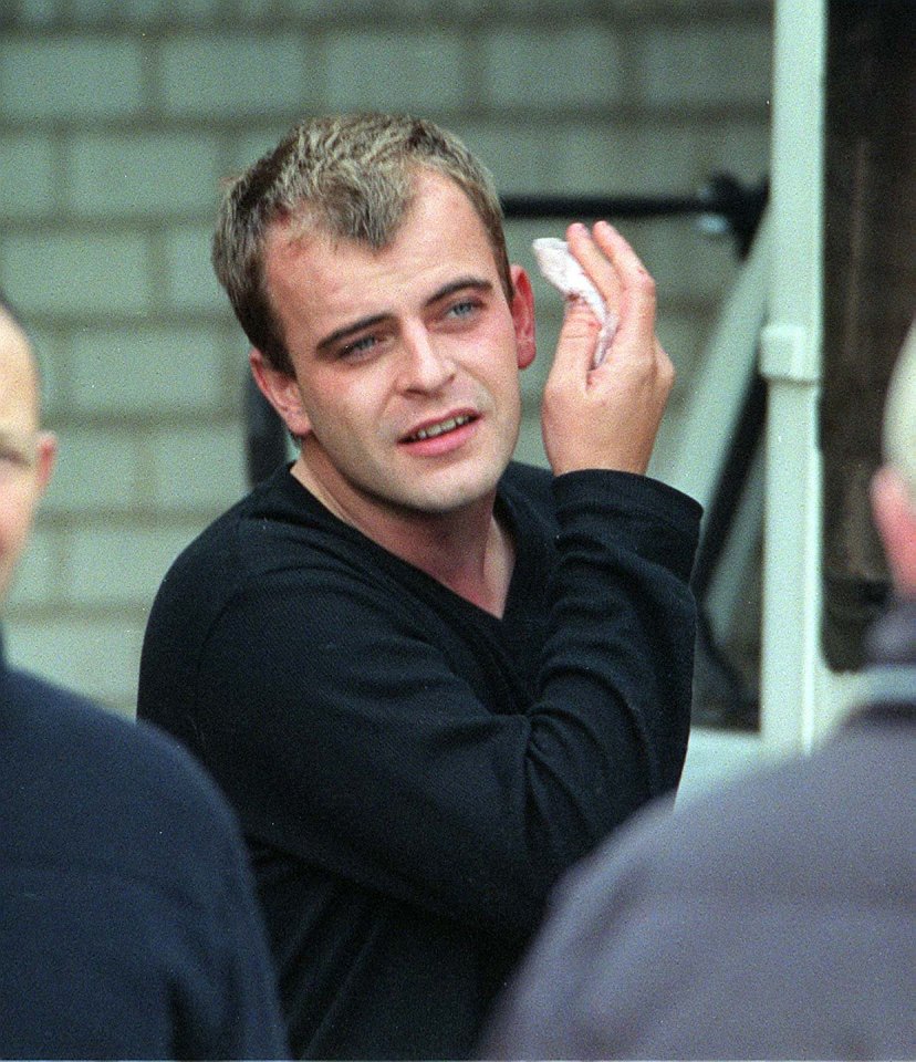 a man in a black shirt wipes his face with a napkin