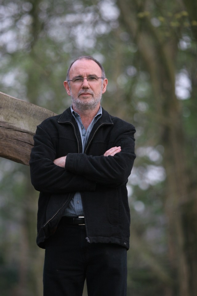 a man in a black jacket stands with his arms crossed