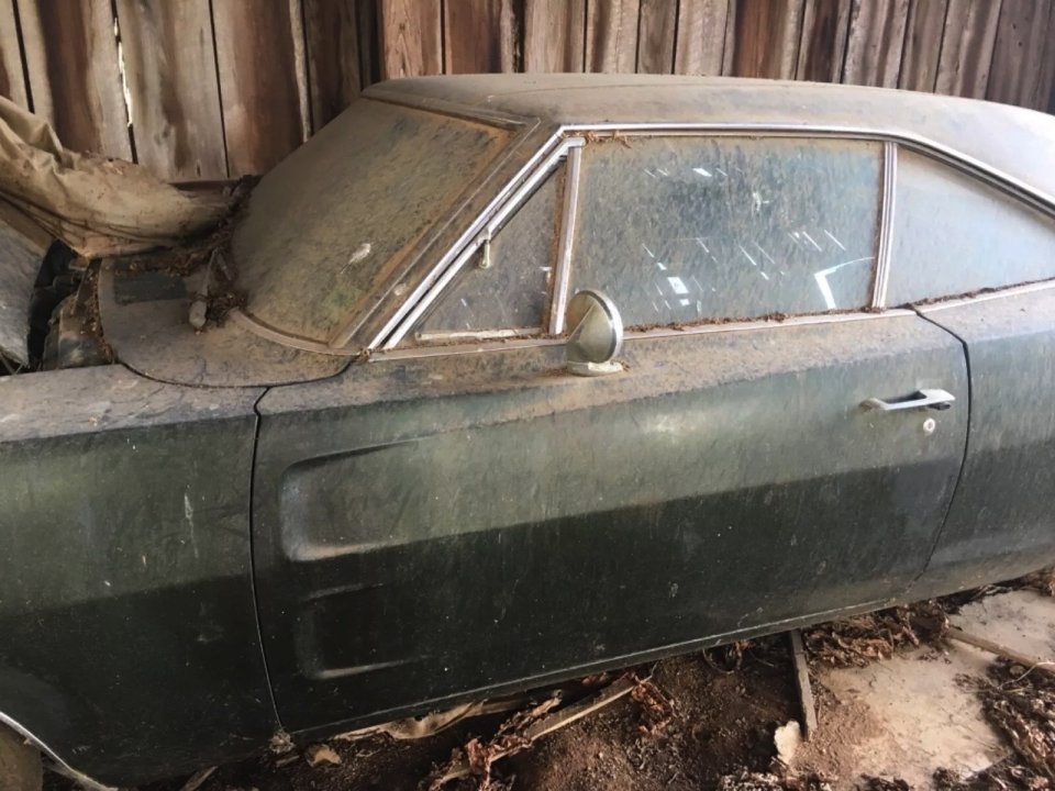 a dirty old car is sitting in a barn