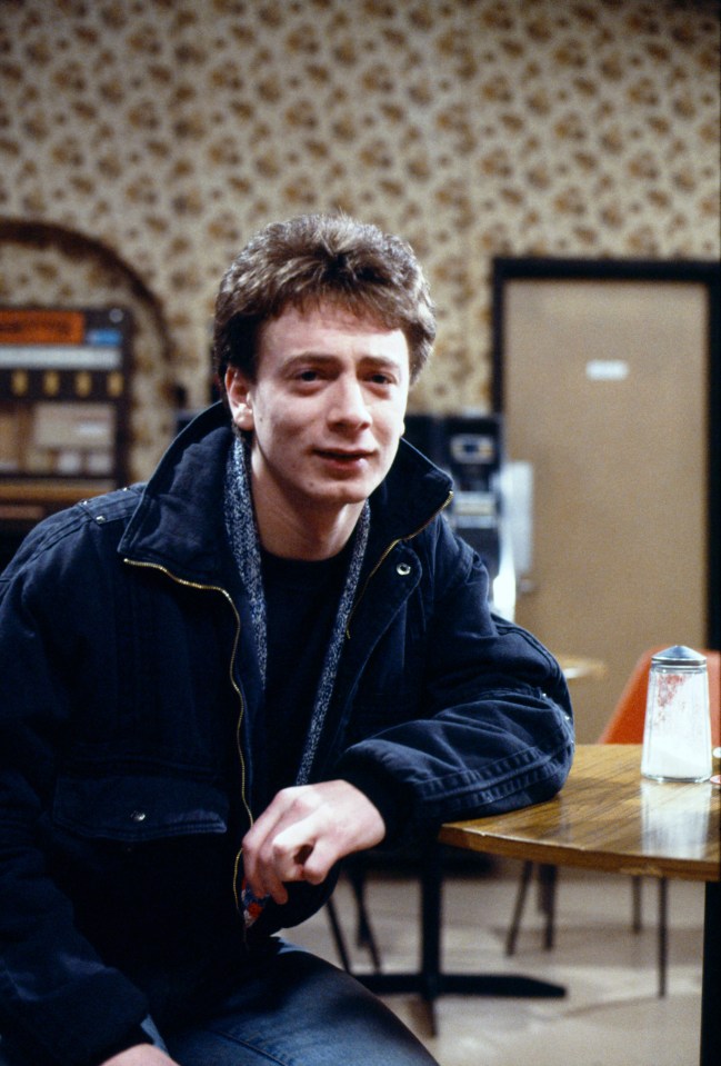 a man in a black jacket sits at a table