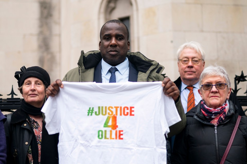 a man holds up a t-shirt that says #justice 4 ollie