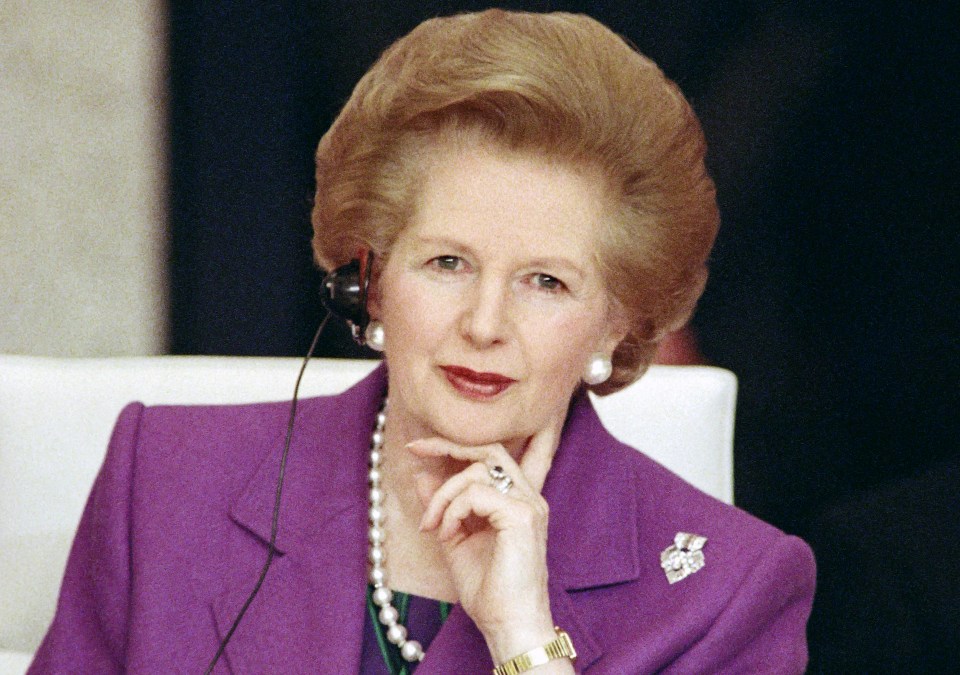 a woman in a purple suit has a pearl necklace around her neck