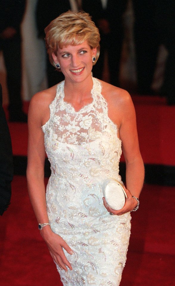 a woman in a white dress is smiling and holding a white clutch