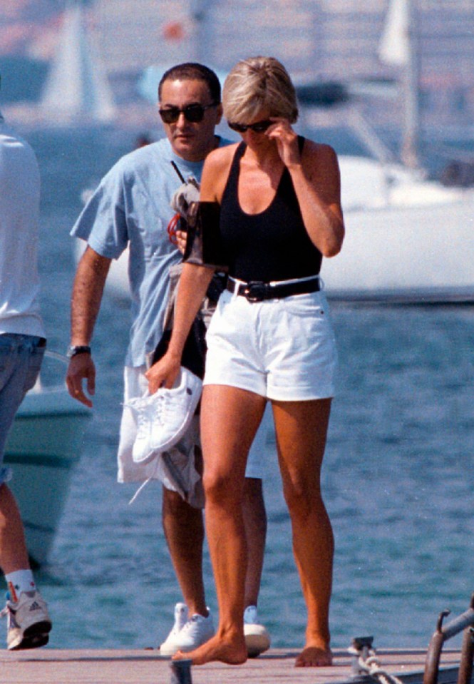 a woman in a black top and white shorts is walking on a dock