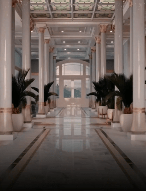 a long hallway with columns and potted plants