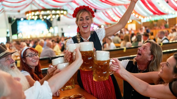 a group of people are toasting with beer mugs