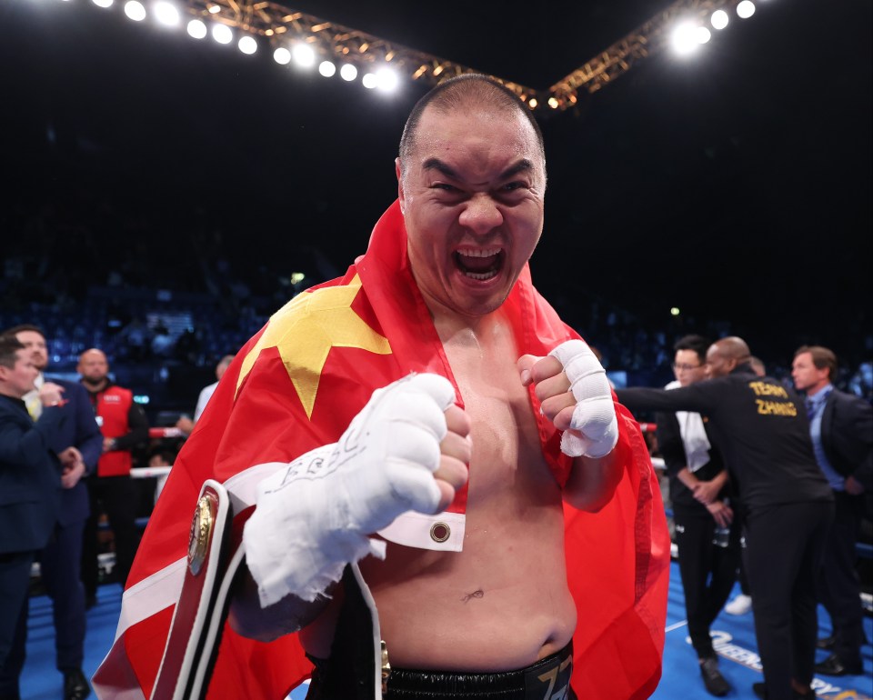 a man in a boxing ring with a yellow shirt that says tom zhang