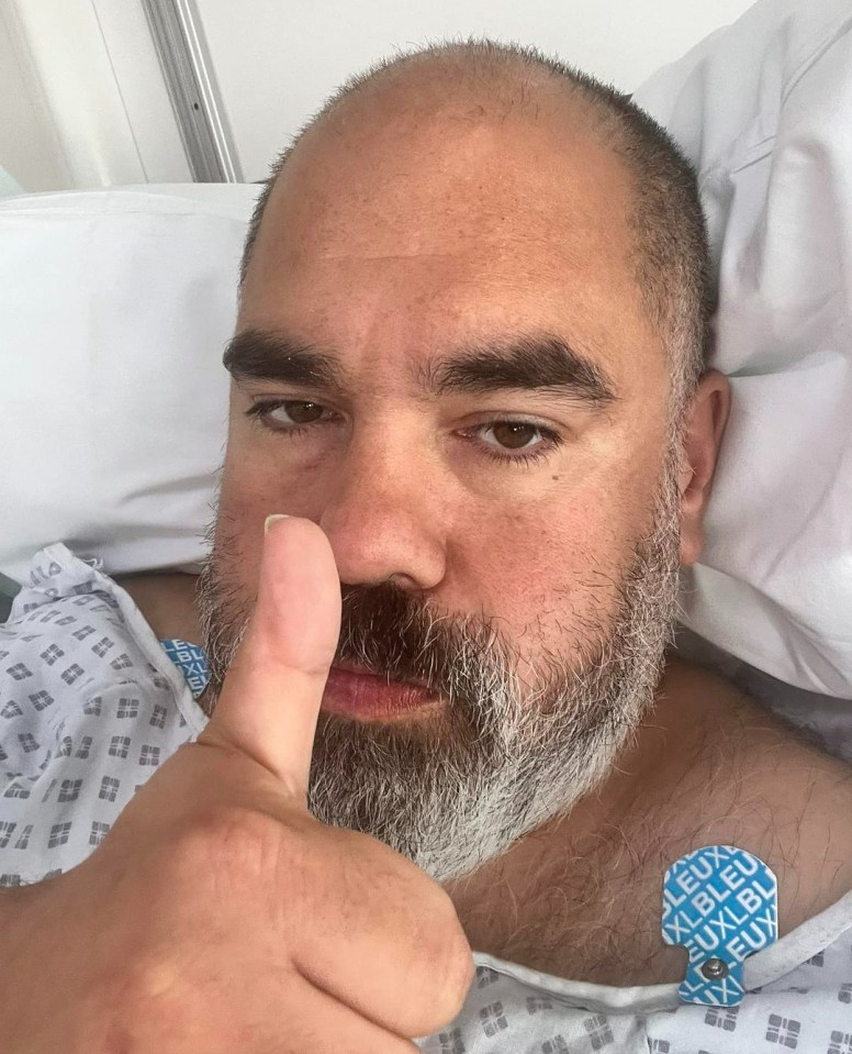 a man in a hospital gown gives a thumbs up