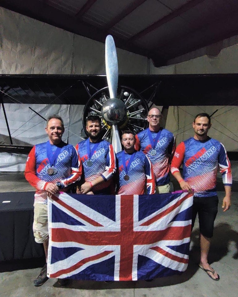 a group of men holding a british flag in front of a plane