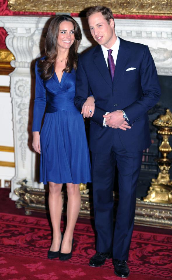 Kate middleton in a blue dress stands next to prince william in a suit