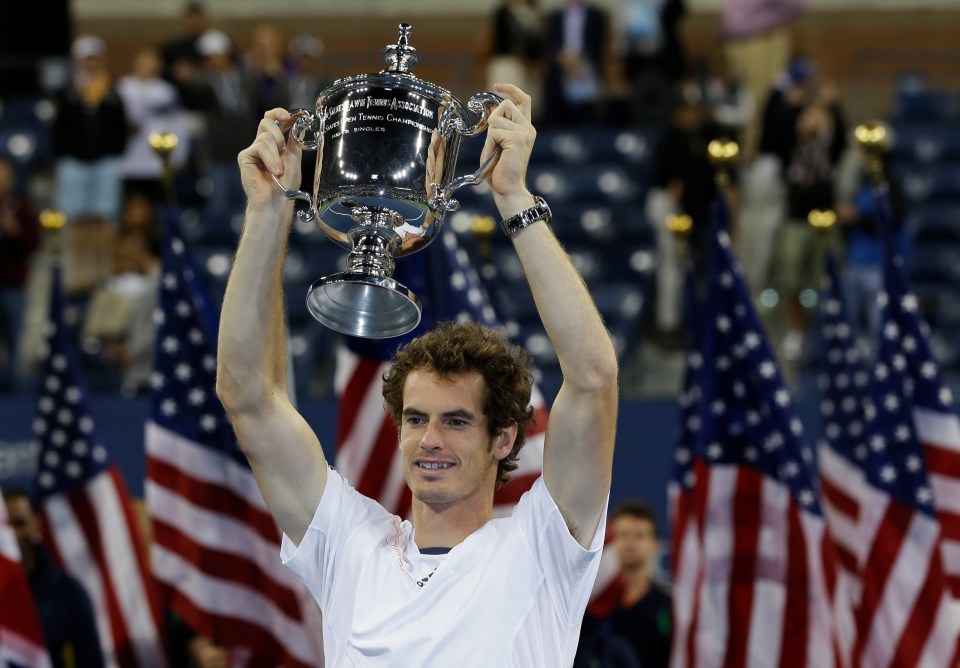 a man holds up a trophy that says us open