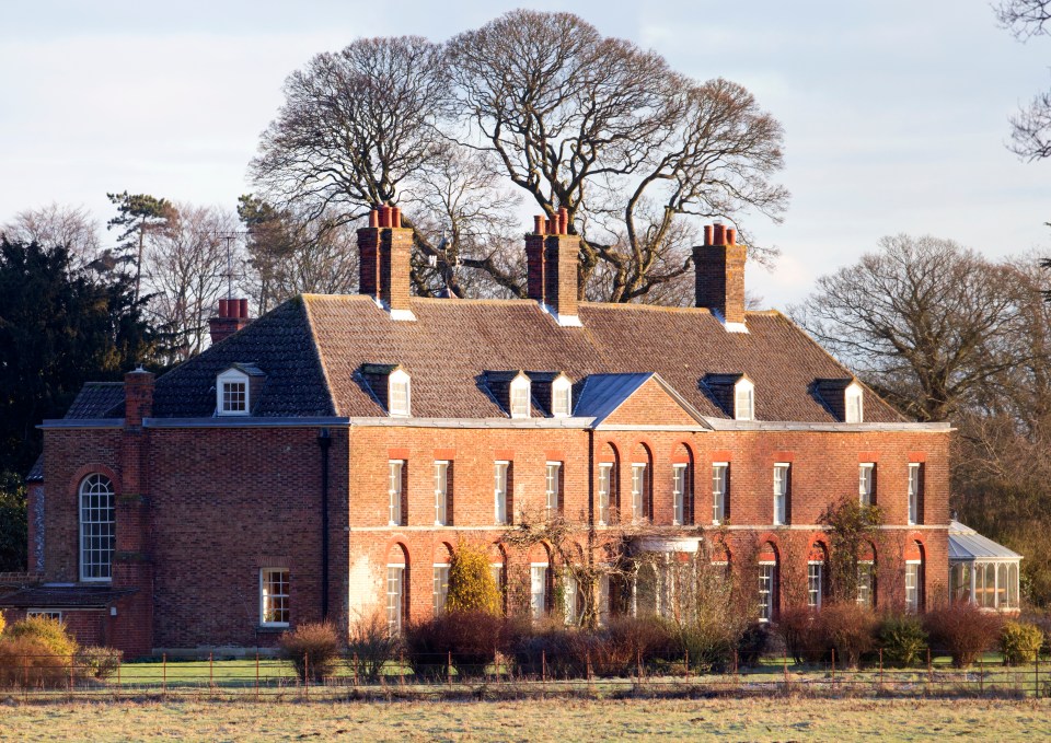 a large brick house sits in the middle of a field