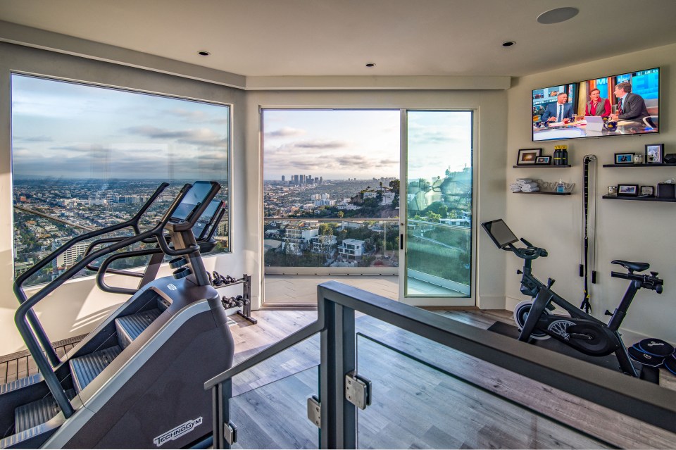 a gym with a view of a city and a tv on the wall