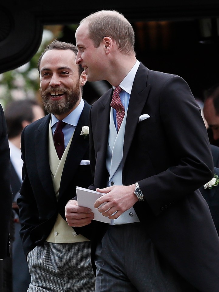 two men in suits are laughing and one has a watch on his wrist