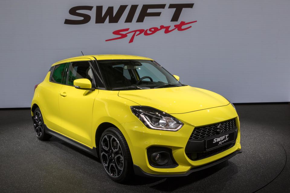 a yellow swift sport is on display in front of a sign that says swift sport