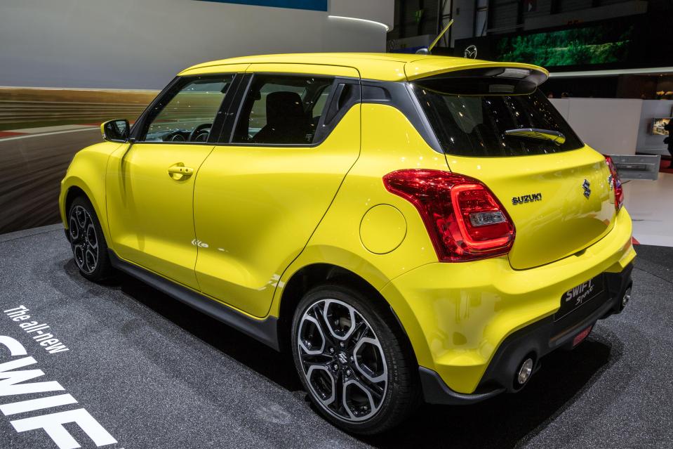 a yellow suzuki car is on display at a car show