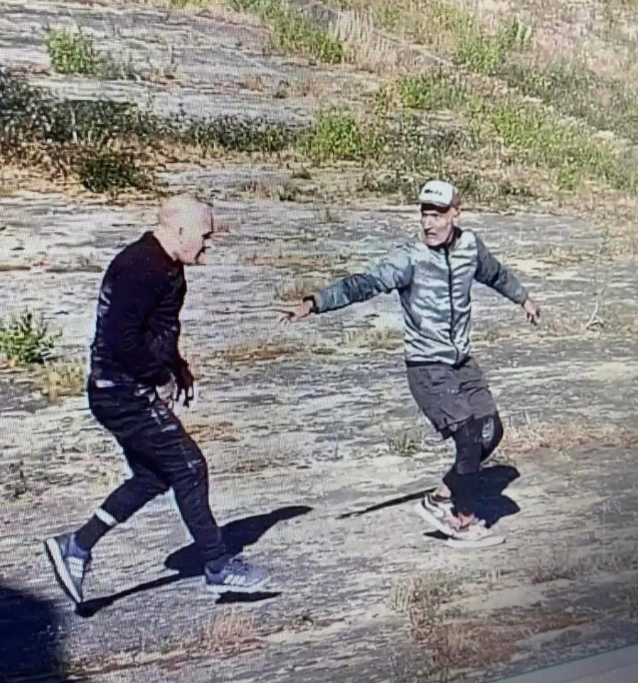 two men are standing next to each other on a dirt road .