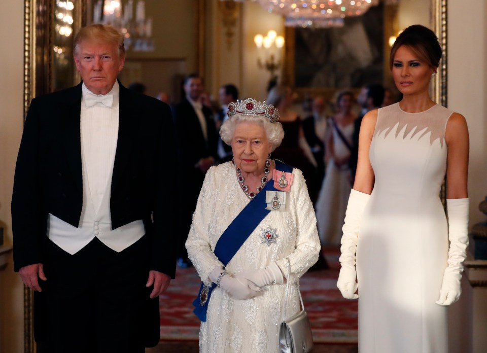 a woman in a white dress stands next to a man in a tuxedo and queen elizabeth ii