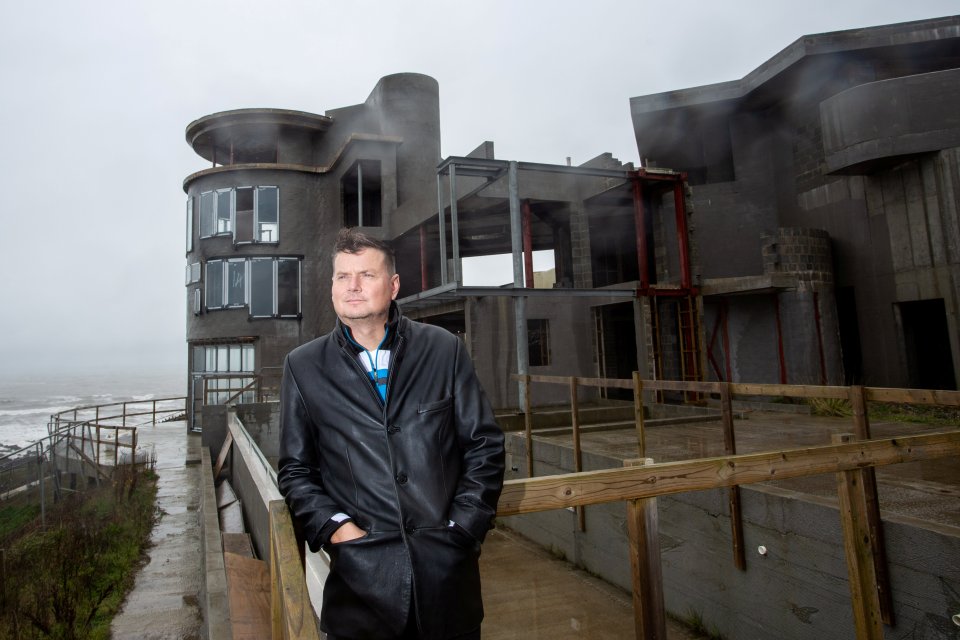 a man in a black coat stands in front of a building under construction