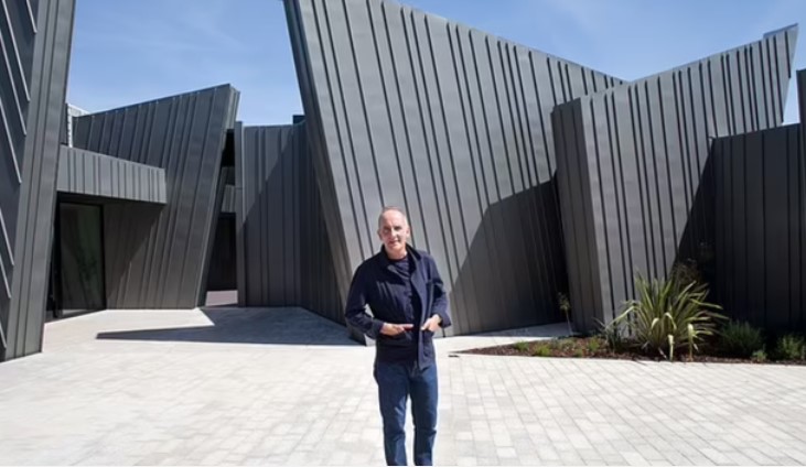 a man standing in front of a building with a gray roof