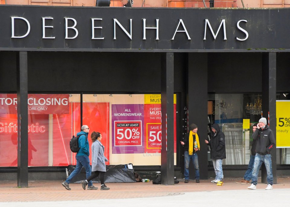 people walking in front of a debenhams store