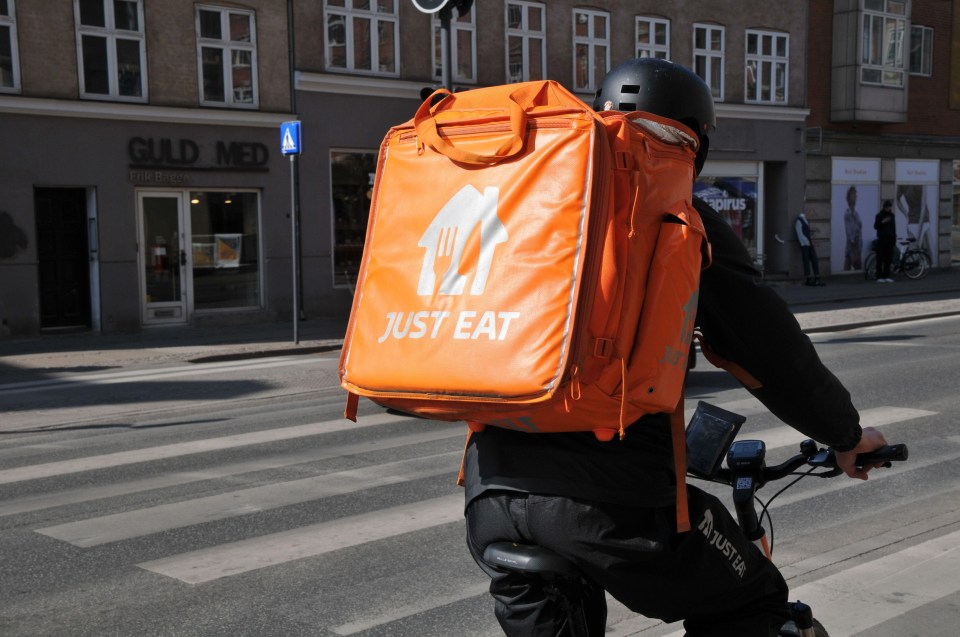 a person riding a bike with a just eat bag on their back