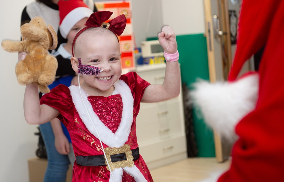 a little girl in a santa outfit is holding a stuffed animal