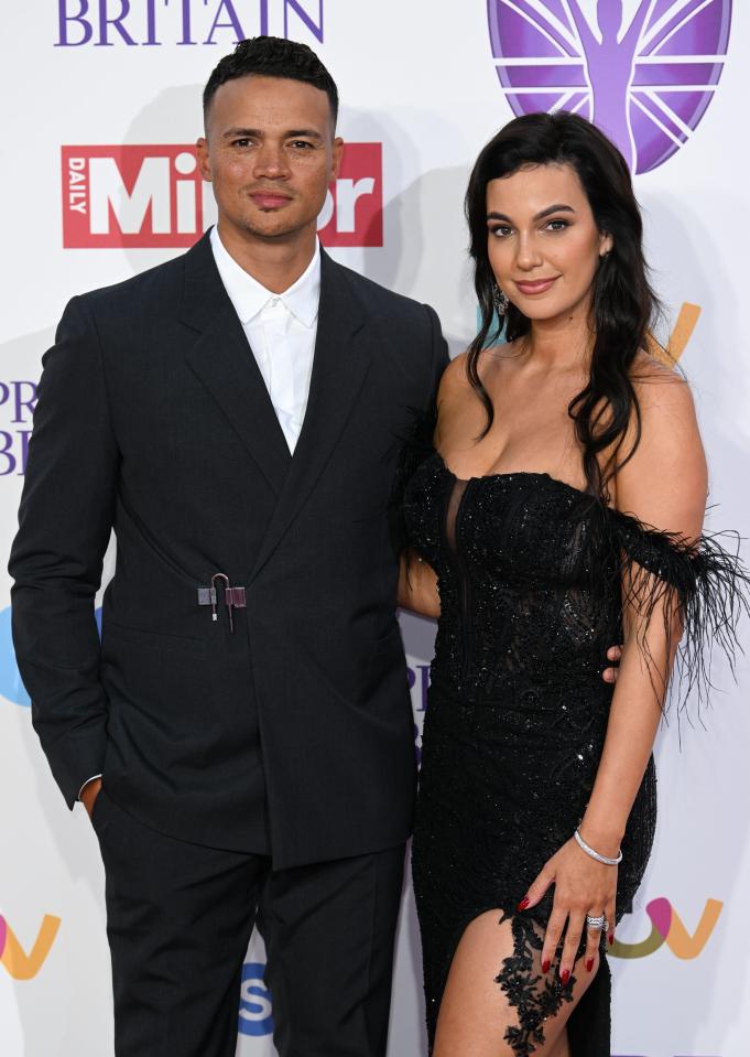 a man and woman pose for a photo in front of a britain daily mirror