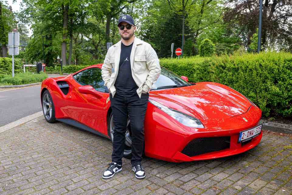 a man is standing next to a red sports car with a license plate that says 2 dmw-434