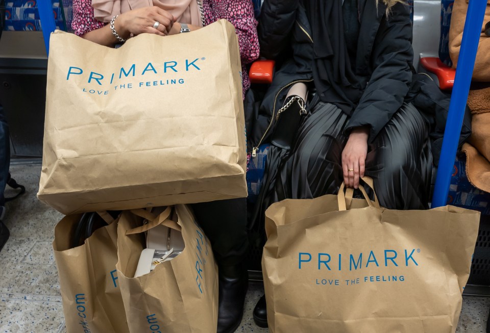 two women sitting on a train holding bags from primark