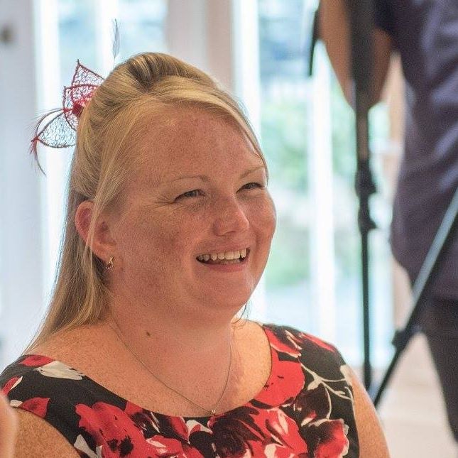 a woman in a red and black floral dress is smiling .