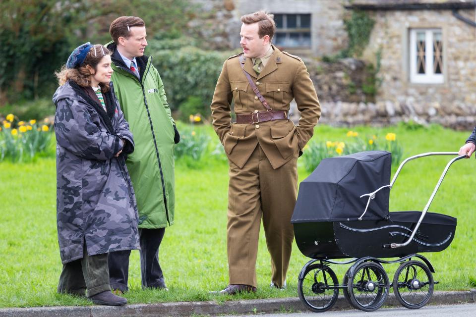 a man in a military uniform stands next to a woman and a baby stroller