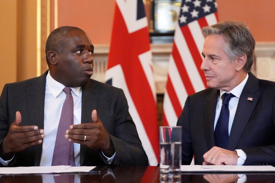 two men are sitting at a table with flags in the background