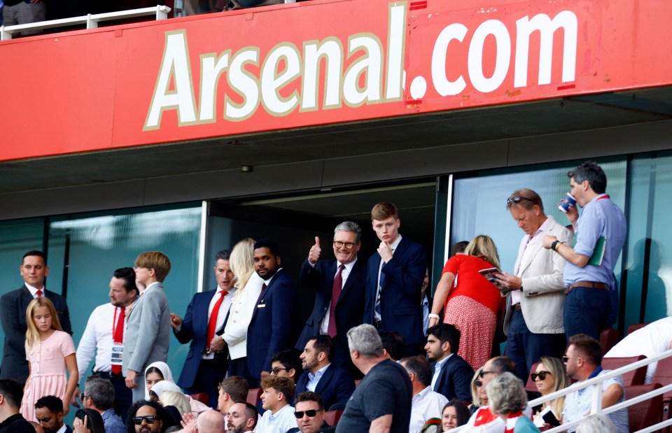 a group of people sitting under a sign that says arsenal.com