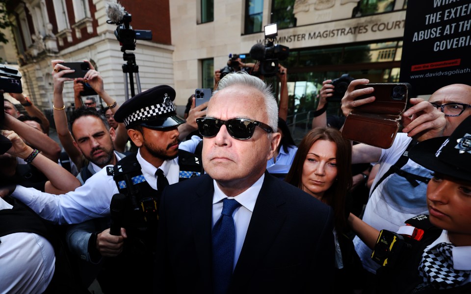 a man wearing sunglasses is surrounded by a crowd of people in front of a building that says minister magistrates court