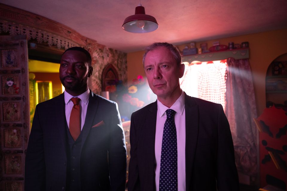 two men in suits and ties are standing in a dark room