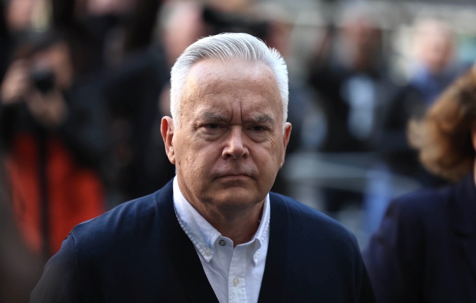 a man in a blue jacket and white shirt looks at the camera