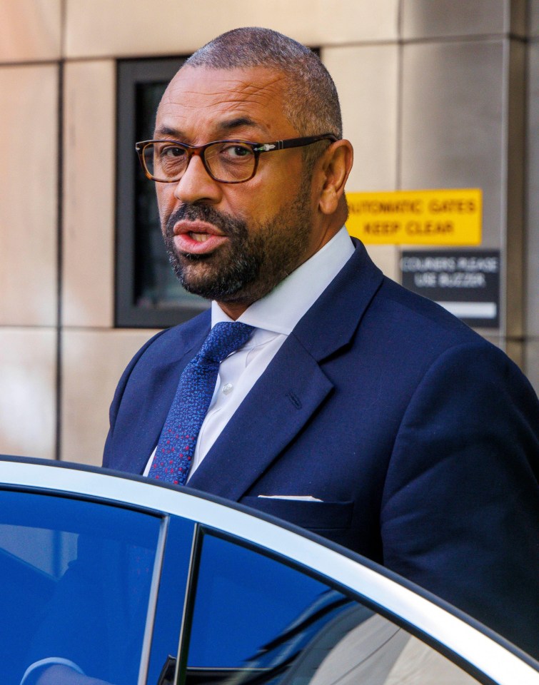 a man in a suit and tie is standing in front of a yellow sign that says automatic gates keep clear